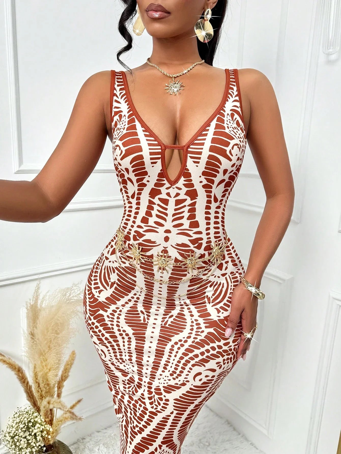 Woman wearing a red and white patterned dress against a white wall.