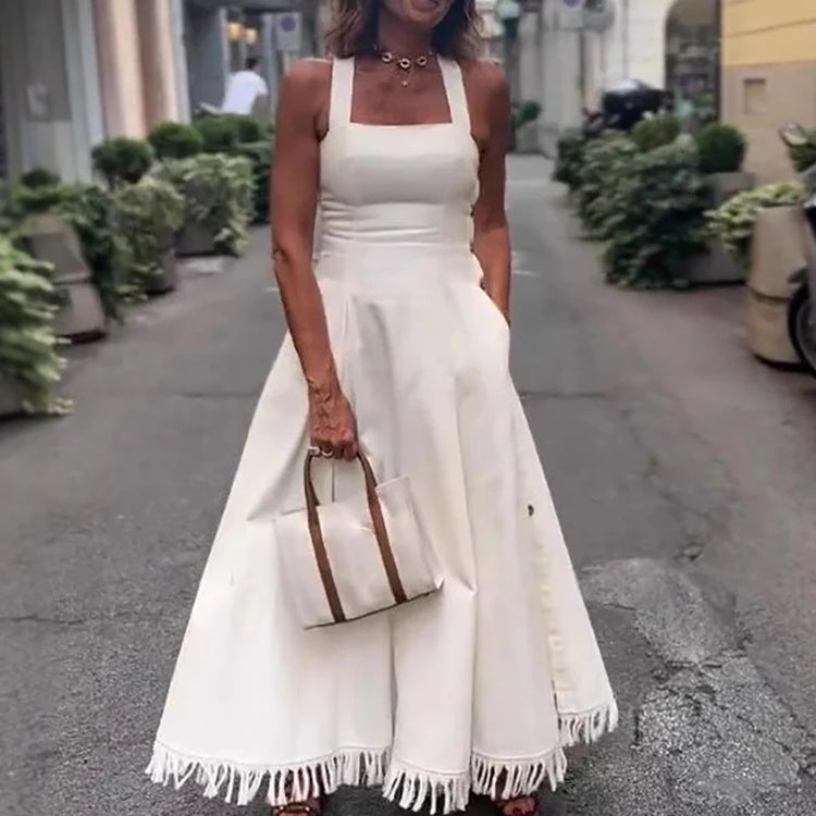 Woman in a white dress holding a matching handbag on a street.