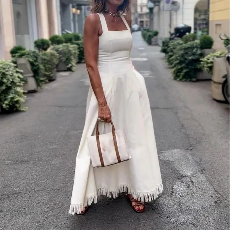 Woman in a white dress holding a handbag on a city street.