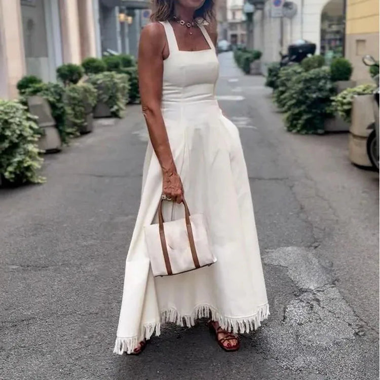 Woman in a white dress holding a handbag on a city street.
