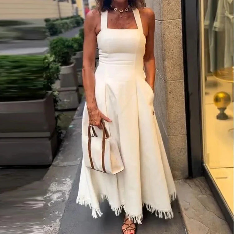 Woman in a white dress holding a handbag on a city street.