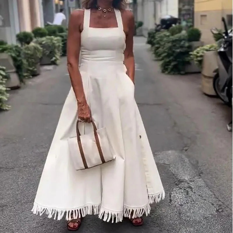 Woman wearing a white dress with fringe details on a street.