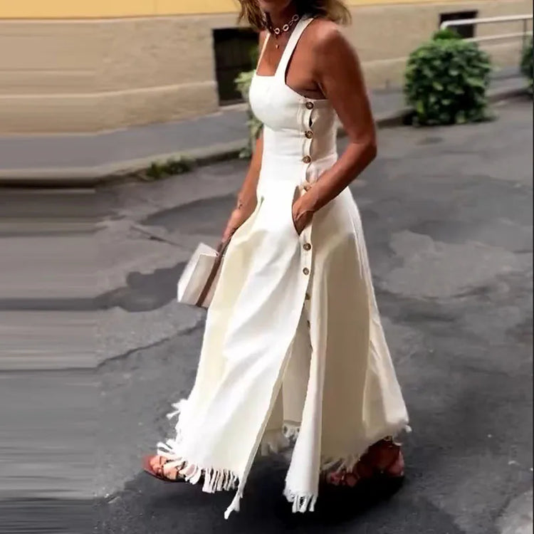Woman wearing a white dress with buttons and fringes on a street.